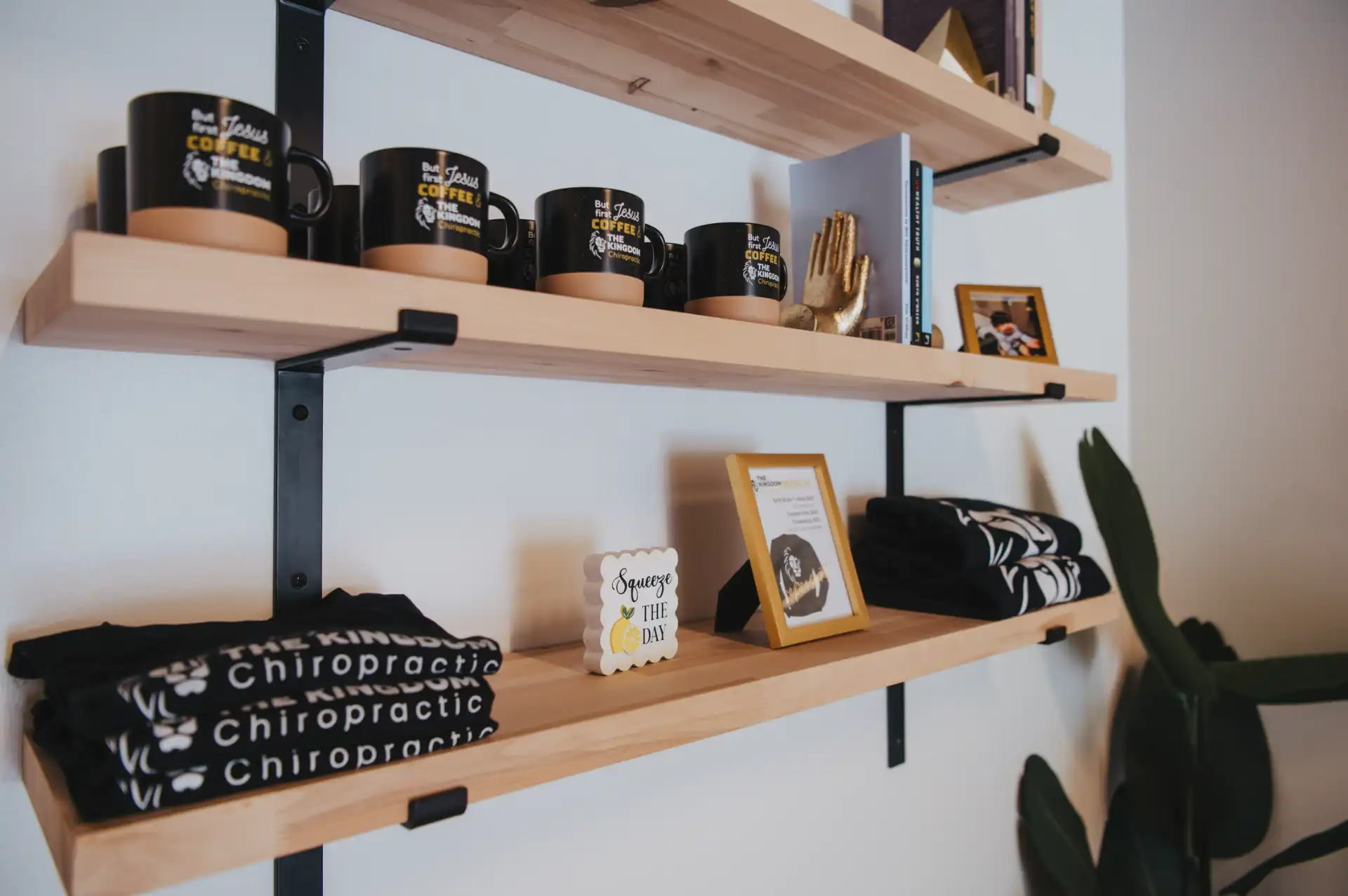Kingdom Chiropractic merchandise shelf with branded mugs, shirts, and decor