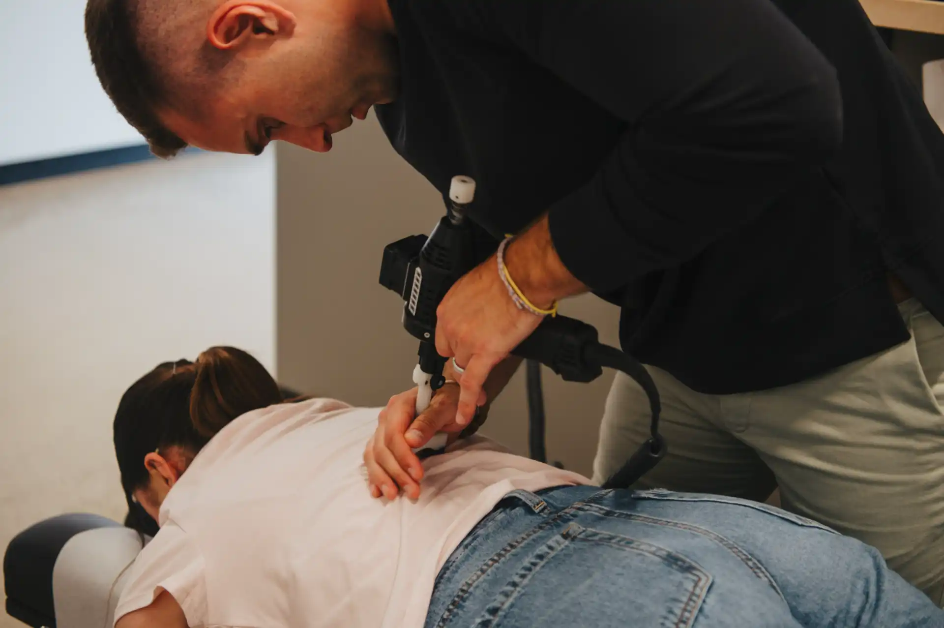 Dr. Sam delivering a precise spinal adjustment with an activator